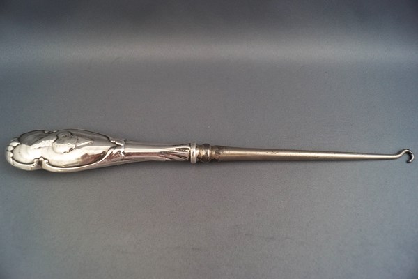 A large Victorian silver handled button hook with embossed cherub's head to handle,