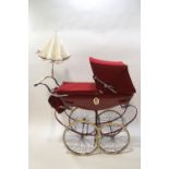 A Silver Cross babies pram with red livery and hood,