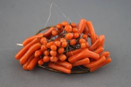 An early 20th century coral abstract cluster brooch of oval outline set with branches and beads,