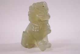 A pale green carved hard stone figure of a dog of foe, one paw nesting on a ball. 6.5cm high.