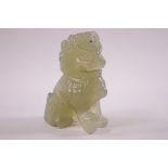 A pale green carved hard stone figure of a dog of foe, one paw nesting on a ball. 6.5cm high.