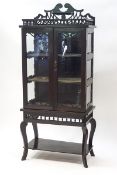 A Victorian ebonised display cabinet, the glazed doors enclosing three shelves,