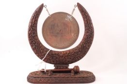 An Indian table gong, the wooden surround extensively carved with stylised plants,