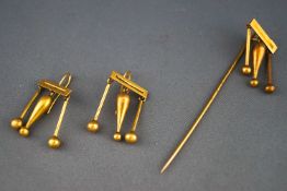 A yellow metal stick pin and a matching pair of drop earrings.
