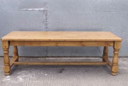A substantial pine kitchen table on turned legs,