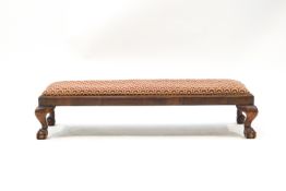 A 19th century rectangular footstool with tapestry cover on ball and claw feet,