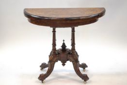 A Victorian walnut demi-lune card table with marquetry top on four column supports and ceramic