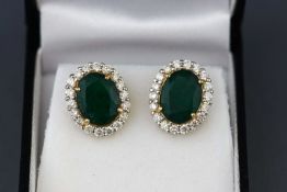 A yellow and white metal pair of emerald and diamond cluster earrings.