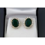 A yellow and white metal pair of emerald and diamond cluster earrings.