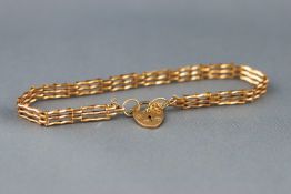 A yellow gold three bar gate bracelet, padlock and safety chain fitting.