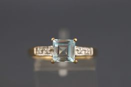 A yellow and white metal dress ring set with aquamarine and diamonds.