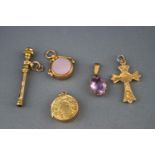 A selection of five gold charms to include a citrine baton, a gold locket,