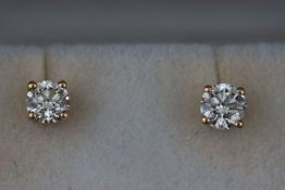 A yellow metal pair of single stone diamond stud earrings. estimated weight of (2) diamonds 0.