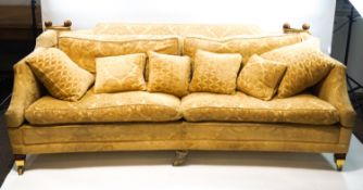 A modern Knowle four seat sofa on square tapering legs with brass casters, gold coloured upholstery,