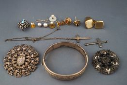 A selection of jewellery to include a silver engraved bangle, three base metal brooches,