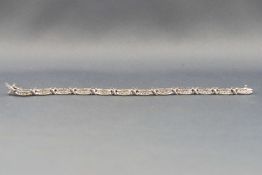 A white metal diamond line bracelet with X and bar design. Estimated weight of (60) diamonds 1.