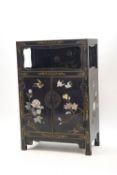 A Chinese lacquered and gilded cupboard with applied hardstone decoration in the form of birds and