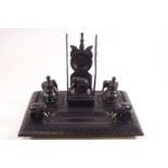 An Indian ebony desk stand carved with elephants and incorporating a pocket watch holder,