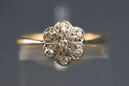 A yellow metal diamond flower cluster ring set with seven old brilliant cut diamonds. Stamped 18ct.