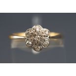 A yellow metal diamond flower cluster ring set with seven old brilliant cut diamonds. Stamped 18ct.