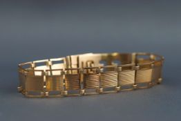A yellow metal pierced panel bracelet with adjustable clasp, stamped "9ct",