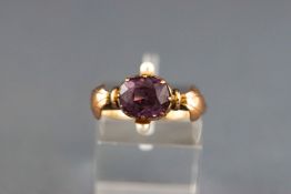 A yellow and rose metal dress ring set with a rhodolite garnet and two seed pearls.