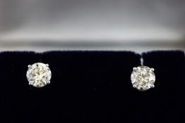 A white metal pair of single stone diamond stud earrings.