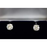 A white metal pair of single stone diamond stud earrings.