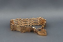 A gold five bar gate bracelet with padlock and safety chain. Stamped LW&C 9ct. 17.
