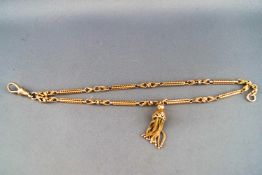 A yellow metal double row bracelet of abstract design with a tassel style charm attached.