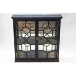 A Victorian ebonised display cabinet with astragal glazed cupboard doors enclosing two shelves and