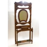 An early 20th century oak hallstand with central horseshoe shape mirror over a lidded storage box