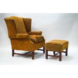 A 20th century wing back armchair with paisley style fabric and matching footstool on reeded legs