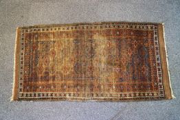 An early 20th century Caucasian rug with repeating gul pattern within four borders on a rust red