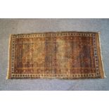 An early 20th century Caucasian rug with repeating gul pattern within four borders on a rust red