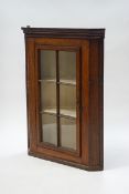 A 19th century oak hanging corner cabinet with a six pane glazed door,