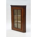 A 19th century oak hanging corner cabinet with a six pane glazed door,