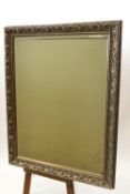 An Art Nouveau style wall mirror with silver effect frame and bevelled glass,