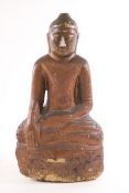A painted and carved stone figure of a Buddha seated in the Lotus position,