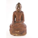 A painted and carved stone figure of a Buddha seated in the Lotus position,