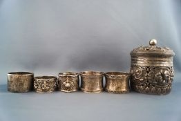 An Indian white metal cylindrical jar and cover, pierced and embossed with figures, 11cm high,