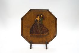 An Art Deco octagonal wooden fire screen, mounted with a flirting couple in period costume,