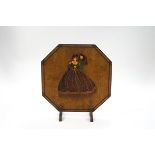 An Art Deco octagonal wooden fire screen, mounted with a flirting couple in period costume,