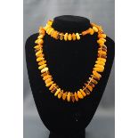 A modern tumble-polished amber bead necklace in transparent and opaque 'butterscotch' colours,