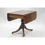 A George IV mahogany Pembroke table on turned column and four splayed legs with brass paw terminals