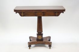 A late Regency rosewood card table with brass inlay,