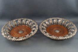 A pair of George III silver coasters with cast flower head and scrolling foliate rims supported by