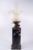 A Victorian oil lamp the cylindrical earthenware body painted with flowers on a blue ground,