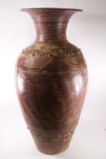 A large decorative floor standing pottery vase with heavily incised swirl pattern,