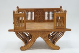 A modern teak seat with pole gallery on out swept legs,